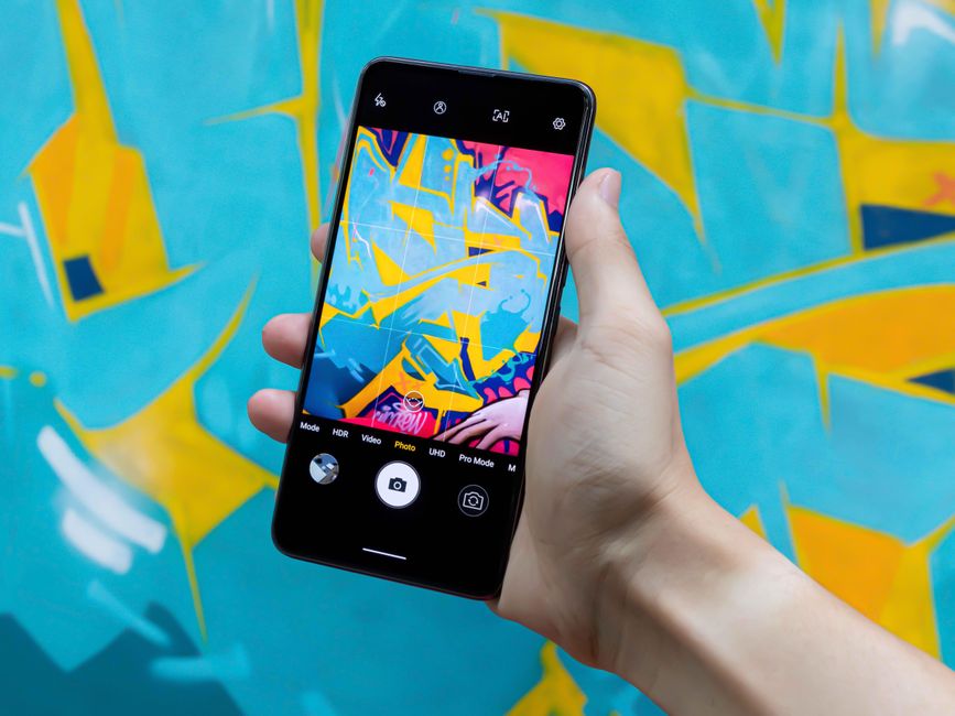 A smartphone captures vibrant abstract graffiti art, showcasing creativity and technology.